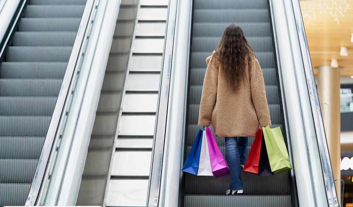 Woman at the mall on escalator with colored shopping bags