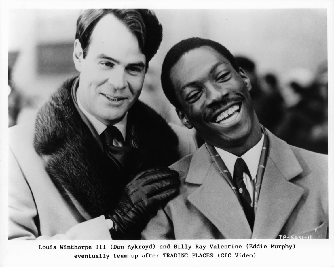 Black-and-white promotional photo of Dan Aykroyd and Eddie Murphy smiling together from the 1983 film Trading Places.